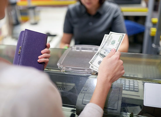A photo of a lady handing over cash to a bank teller