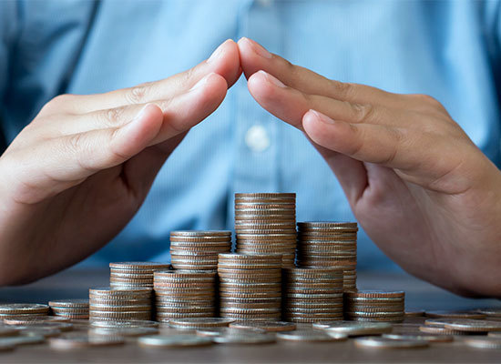 a person protecting a pile of coins with his hands