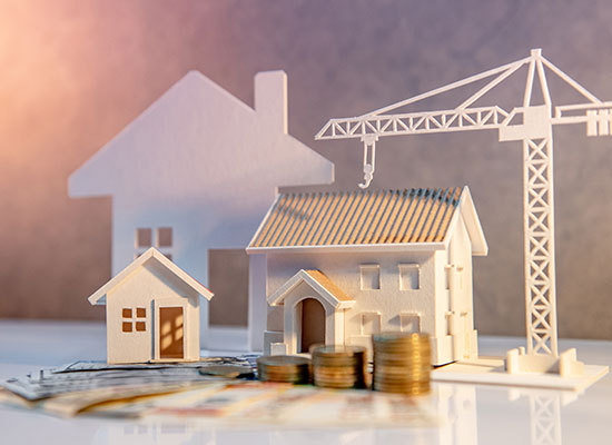 a model home being built with a stack of coins next to it