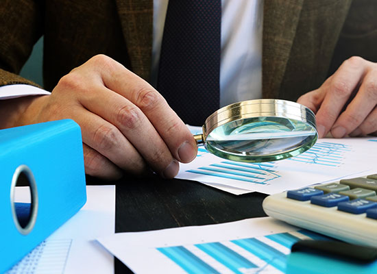 someone using a mgnifying glass to look at a chart