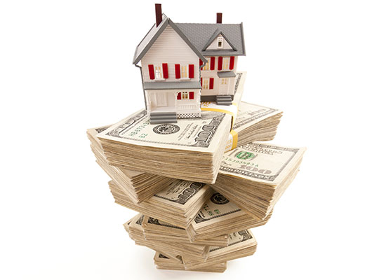 stacks of money with a model house on top