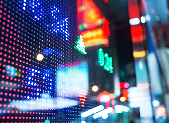 Close-up of a vibrant digital display with multicolored lights and blurred urban background, suggesting a lively city atmosphere at night.