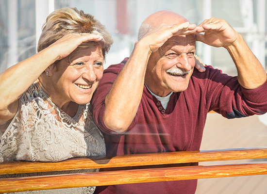 An elderly couple shades their eyes while smiling, symbolizing a positive outlook on retirement planning and future financial security.