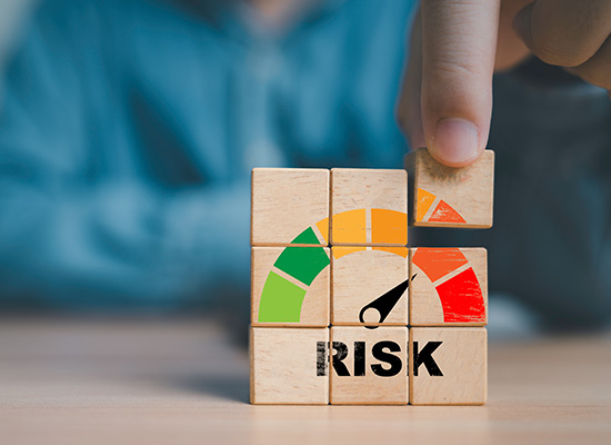 A hand arranges wooden blocks displaying a risk meter, illustrating the concept of financial risk assessment.