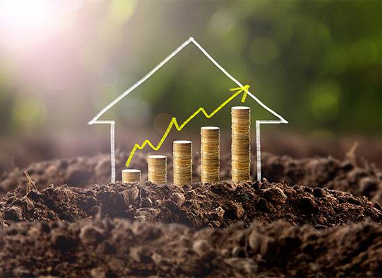 A series of stacked gold coins displayed on soil gradually increasing in height, forming a diagonal line upwards. An arrow line graph is superimposed over the stacks, indicating growth, with a white outline of a house encompassing the graph and stacks—ideal for illustrating financial planning.
