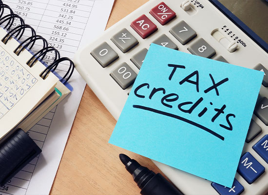 A calculator with a sticky note labeled 'Tax credits' sits on a desk, hinting at retirement planning.