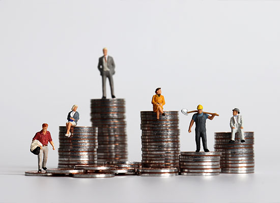 Miniature figures of workers and professionals stand on stacked coins, symbolizing economic disparity and career progression, with a nod to retirement planning