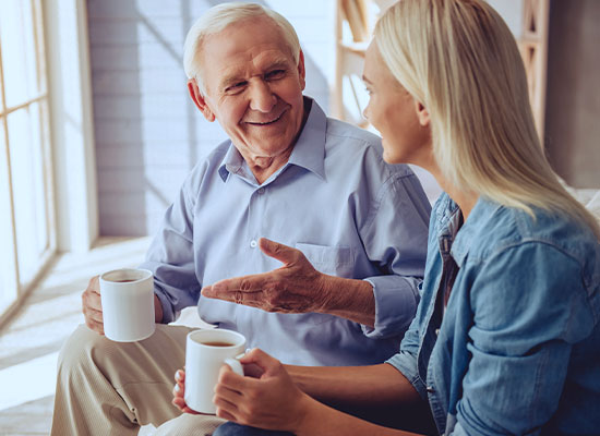 A parent talking with his daughter while both are drinking coffee