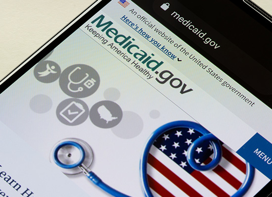 A smartphone screen displays the medicaid.gov website, highlighting healthcare resources for keeping America healthy.