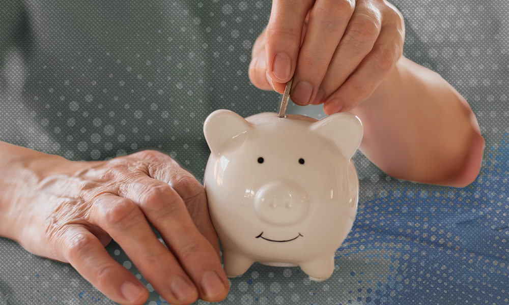 A young hand inserts a coin into a piggy bank held by an older, wrinkled hand, symbolizing the financial planning challenges faced by caregivers preparing for retirement.