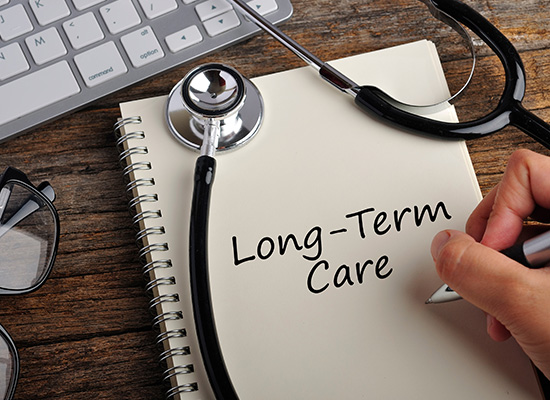 A stethoscope resting on a notebook with the words 'Long-Term Care,' representing the planning caregivers must undertake for their elderly loved ones and themselves.