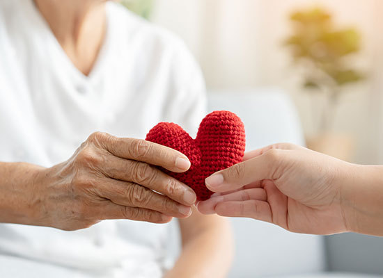a knitted heart being passed from one person to another