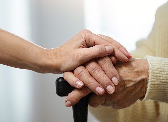 caregiver hand on top of elder pair of hands