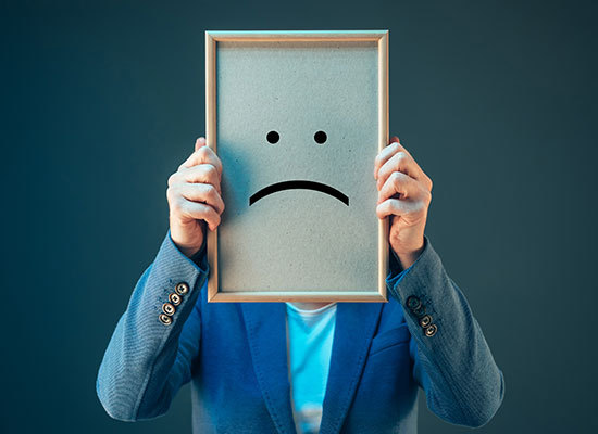 person holding picture in front of their face with a sad face inside