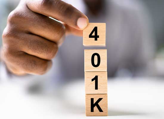 A hand stacking blocks spelling '401K' highlighting the act of building or managing a retirement savings plan.