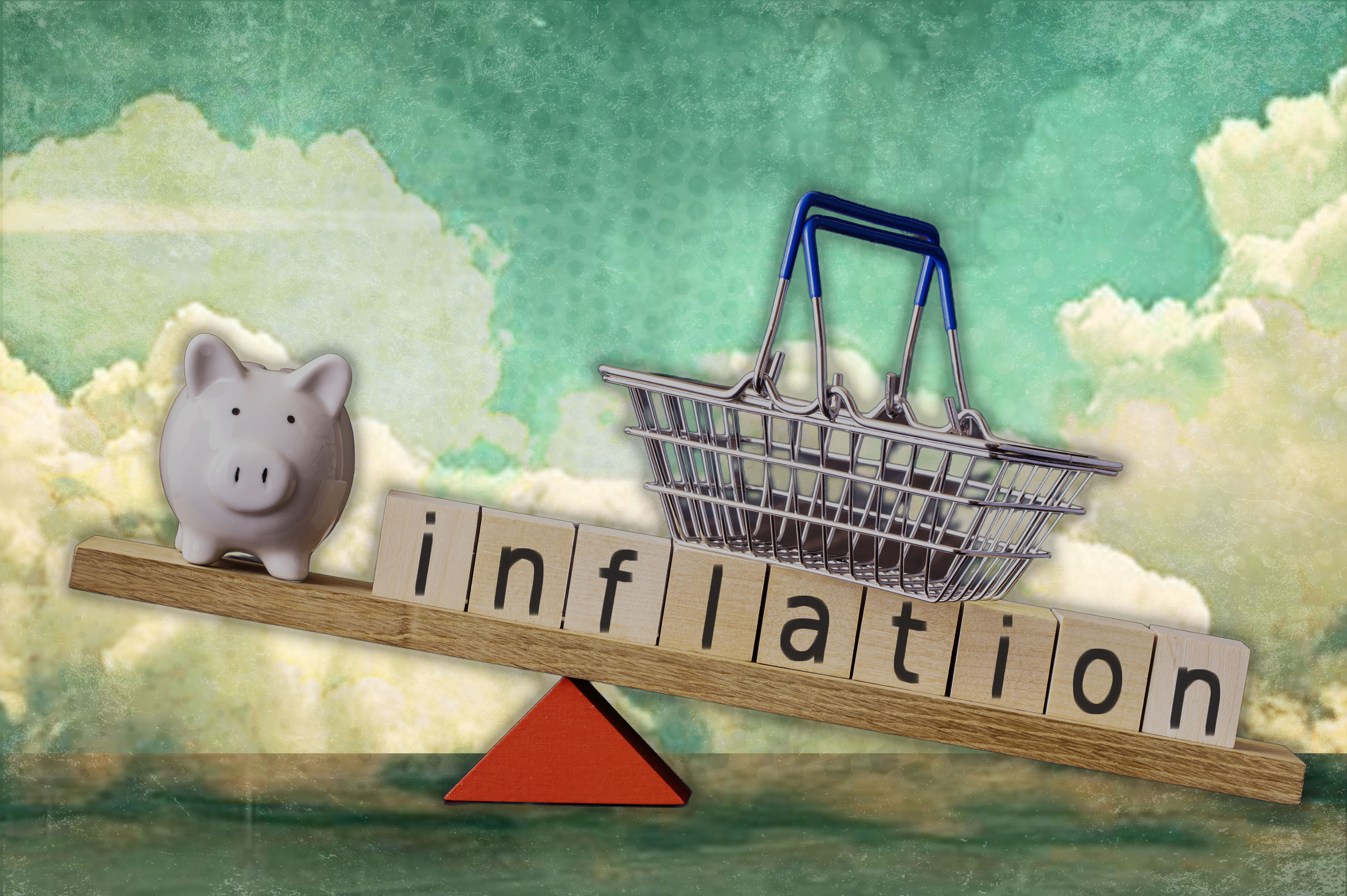 The image depicts a balancing scale with a piggy bank on one side and a shopping basket on the other, with the word 'inflation' spelled out in wooden blocks, symbolizing the impact of inflation on savings and purchasing power.