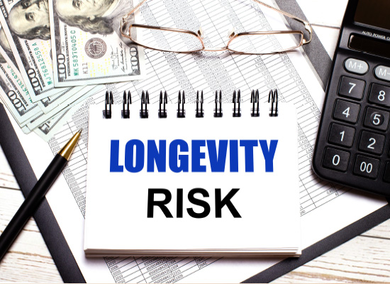 A notepad with 'LONGEVITY RISK' written on it, surrounded by financial tools, highlights the importance of income planning for extended retirement periods.