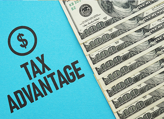  A stack of hundred-dollar bills next to a sign that reads 'Tax Advantage,' highlighting the benefits of Health Savings Accounts (HSA) and Flexible Spending Accounts (FSA).