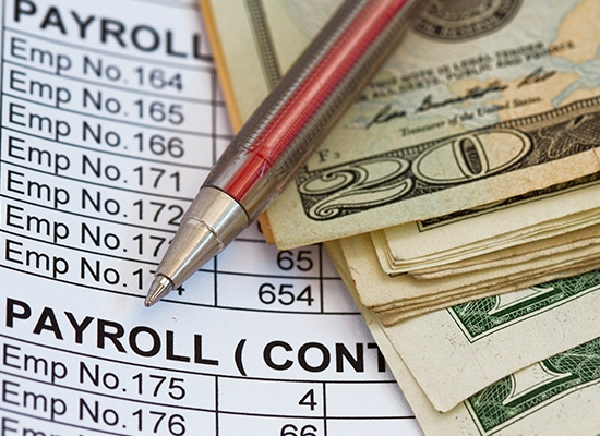 A payroll document with cash and a pen, emphasizing the importance of understanding HSA vs. FSA and their respective advantages.