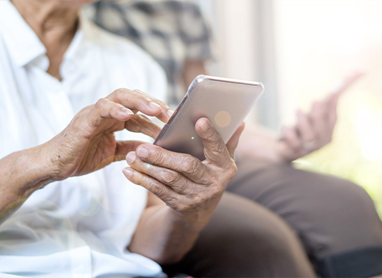 An elderly person taps their smartphone screen, possibly exploring retirement planning options