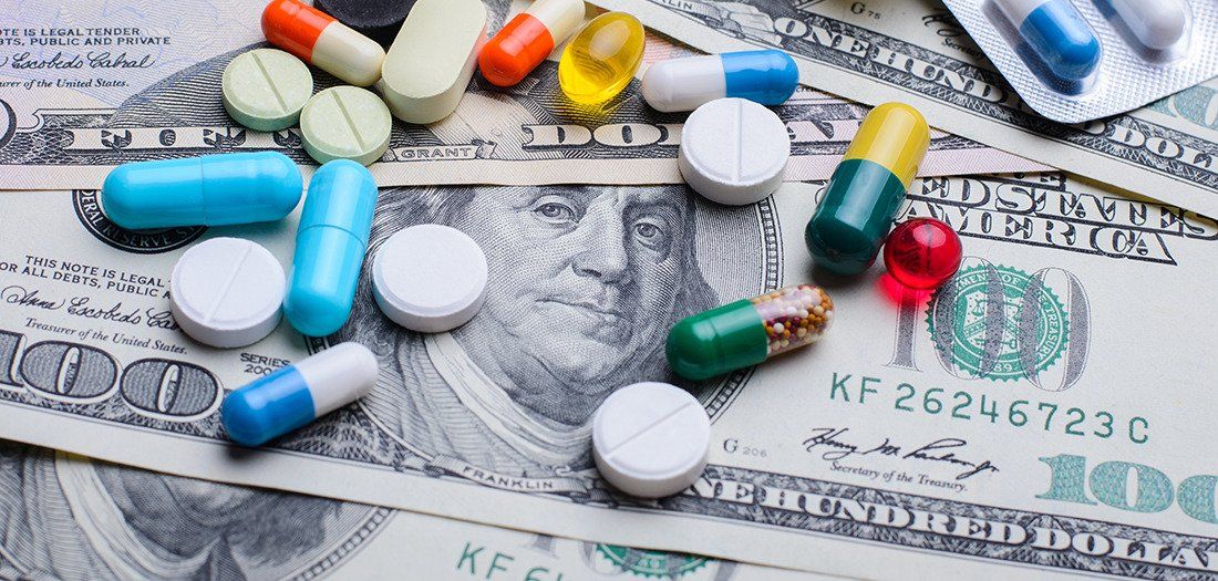 One hundred dollar bills covered with prescription pills