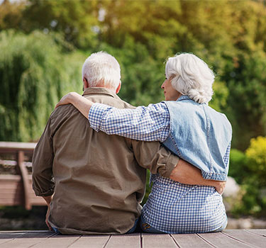 an older couple sitting together and hugging because they are stressed about future financial decisions