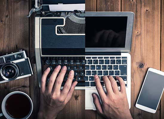 one hand typing on typewriter with transition to other hand on laptop keyboard