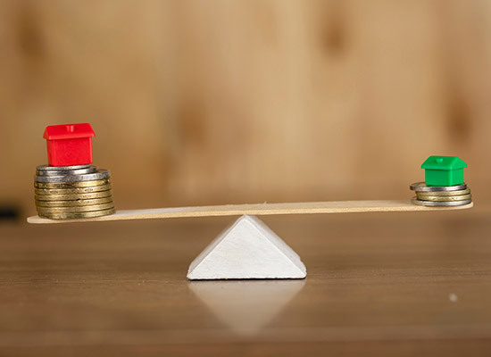 representation of a house and money balanced on a popsicle stick