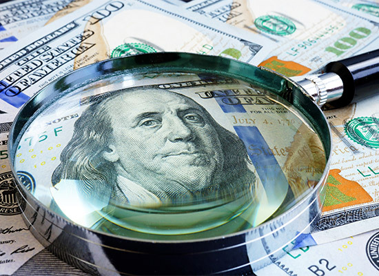 pile of money with a magnifying glass on George Washington's face
