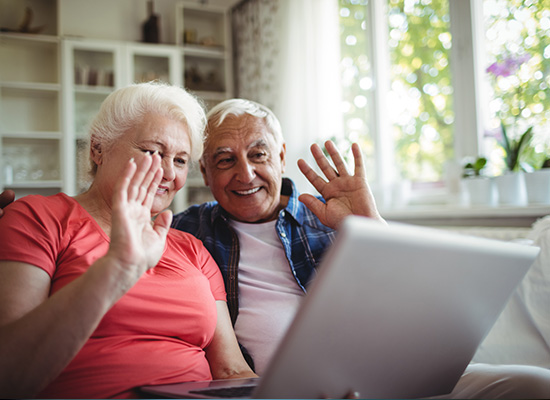 Elderly couple using AI technology for virtual communication to stay connected with loved ones, promoting senior independence and well-being.