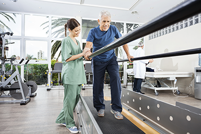 Senior man in physical therapy assisted by nurse
