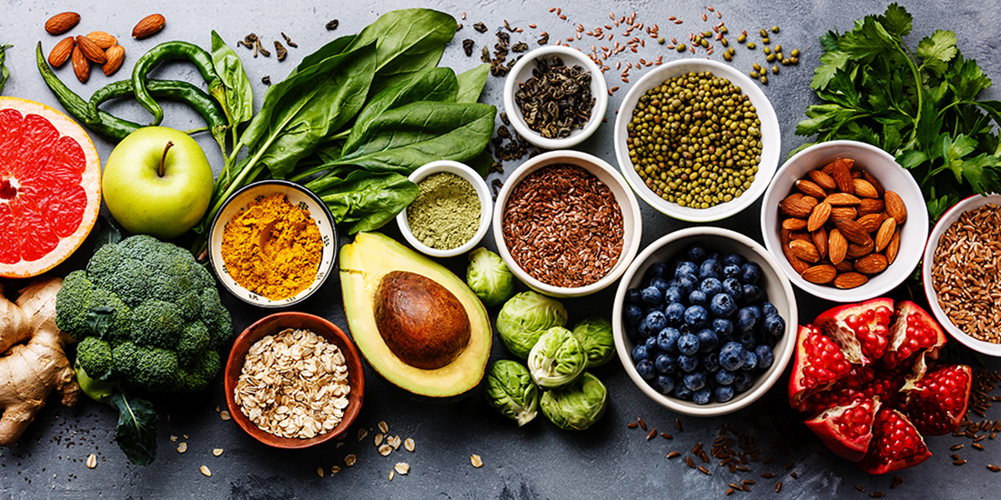Table full of superfoods such as blueberries, avocado, broccoli and grapefruit