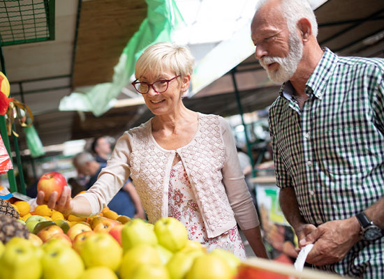 A photo of a couple shopping for various fruits