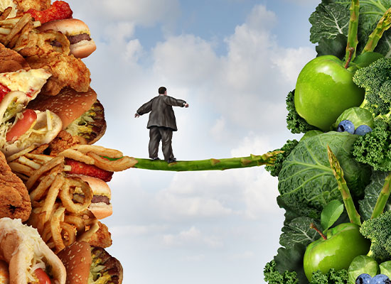  a man walking on a branch connecting a pile of unhealthy food leading towards a pile of healthy foods