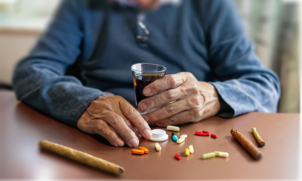elderly man sitting at a table with different pills to take