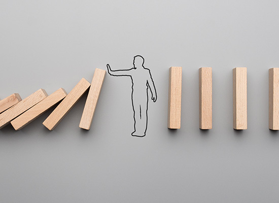 wooden domino's falling with a silhouette of a person holding them up