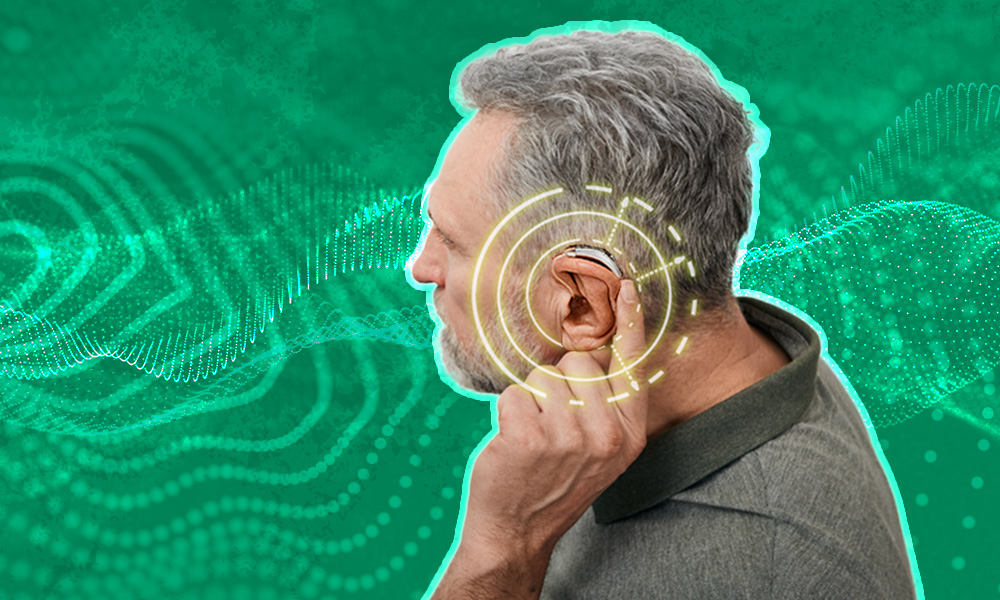 An older man adjusting his hearing aid, with digital sound waves and concentric circles illustrating enhanced hearing, set against a green abstract background.