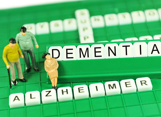 Miniature figures and Scrabble tiles spelling 'Dementia' and 'Alzheimer'.
