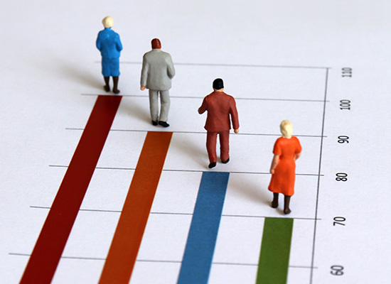 Miniature figures walking on a bar graph symbolizing health-based retirement planning, lifespan, and financial progress in retirement.