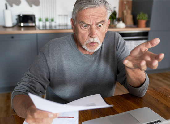 An image of a shocked man looking at a medical bill, representing the surprise and confusion that can arise from complex surgical billing codes and healthcare billing practices