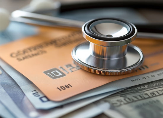 Close-up of a stethoscope on top of money and a credit card, representing medical procedure costs and health care billing, including the impact of surgical billing codes on physician reimbursement.