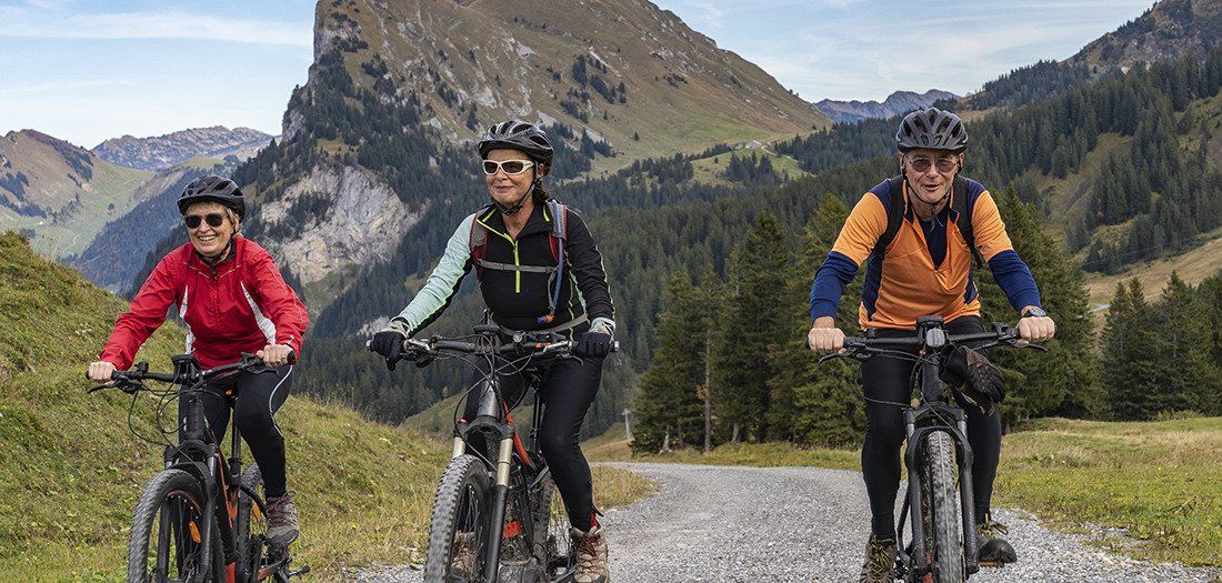 Three older adults bike riding through the mountains