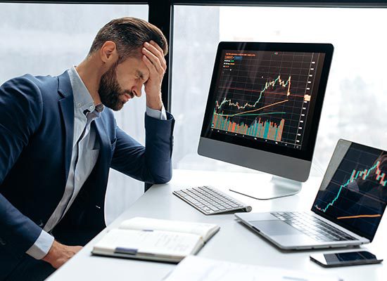 male at desk with hand on forehead