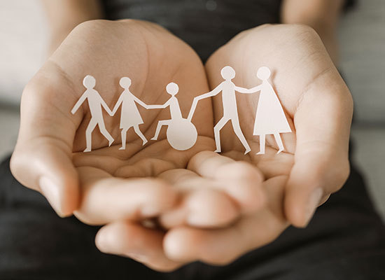 hands holding paper cut outs of people with disabilities