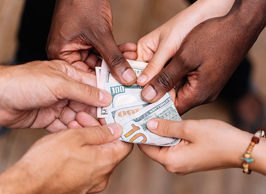 several sets of hands all reaching for the same stack of money