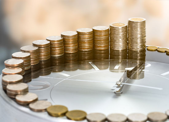 Stacks of coins increasing in height arranged in a semi-circle on a reflective surface, symbolizing financial growth or savings.