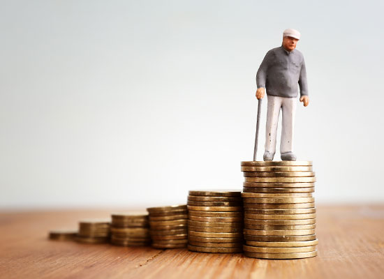 Miniature elderly man standing on the highest stack of ascending coin piles, symbolizing retirement savings or financial growth, against a plain backdrop.