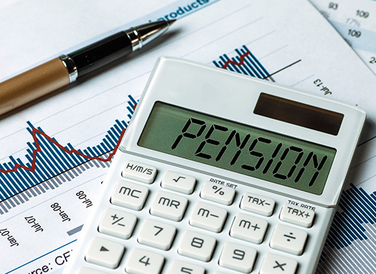 A calculator displaying 'PENSION' on financial documents with graphs, representing defined benefit pensions and retirement planning.