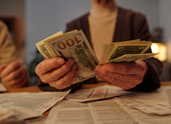 Person counting money as part of retirement income planning and investment strategy.