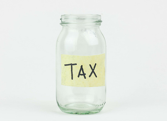 Empty jar labeled 'TAX' highlighting the importance of tax considerations in retirement income planning.
